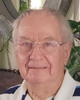 Smiling man with grey hair and glasses.